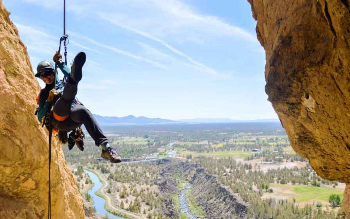 a person poses for a photo midair while rappelling 
